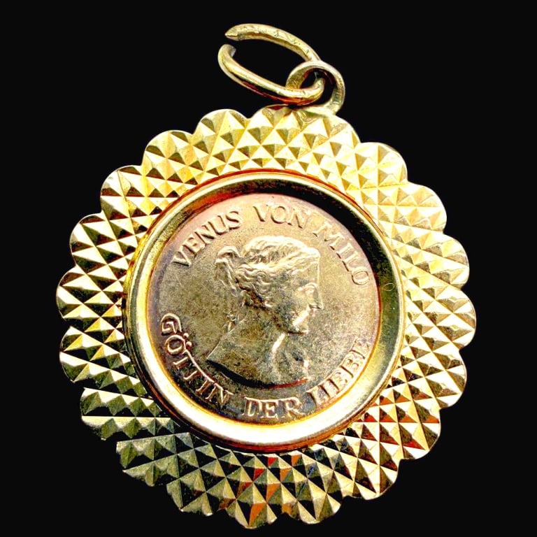 GERMAN VENUS DE MILO COIN PENDANT IN 14K GOLD: 14K GOLD VENUS VON MILO GERMAN MEDALLION PENDANT | | Vintage 14K yellow gold pendant featuring a German Venus von Milo commemorative medallion set within an elaborate circular gold frame. The central 