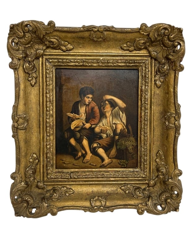 ANTIQUE EUROPEAN GENRE OIL PAINTING 13": Antique European genre oil painting depicting two young men seated together in a rustic interior, one holding food while his companion reclines beside a basket of grapes and raises a cluster of grapes