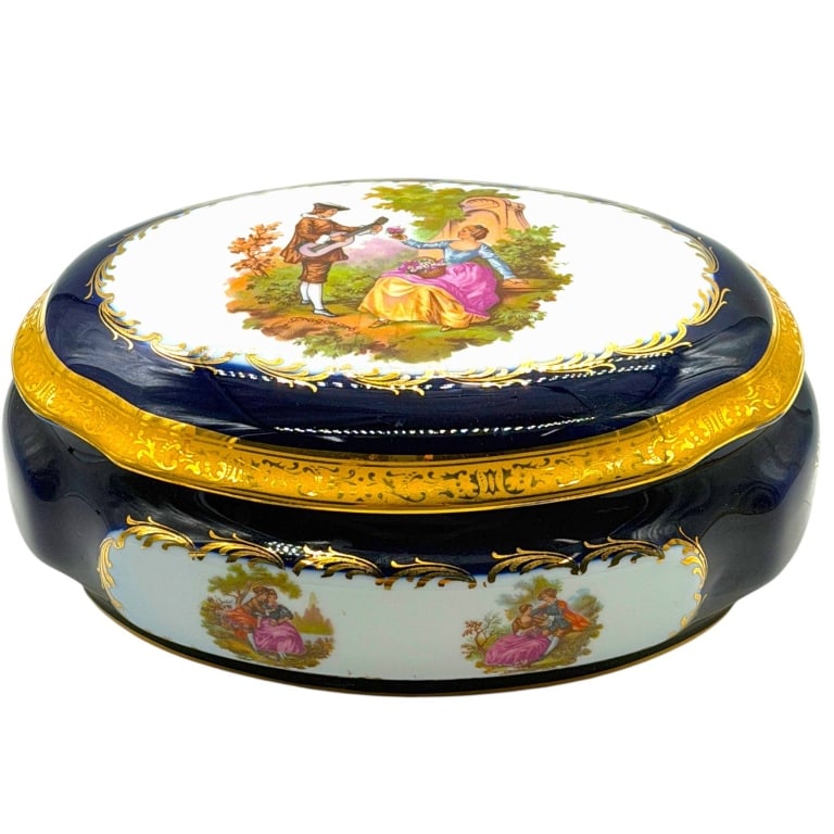 LIMOGES FRAGONARD COBALT PORCELAIN BOX 8": Elegant French Limoges porcelain covered vanity, jewelry or dresser box in rich cobalt blue with extensive gilt decoration. The shaped oval form features white porcelain reserves decorated with romant