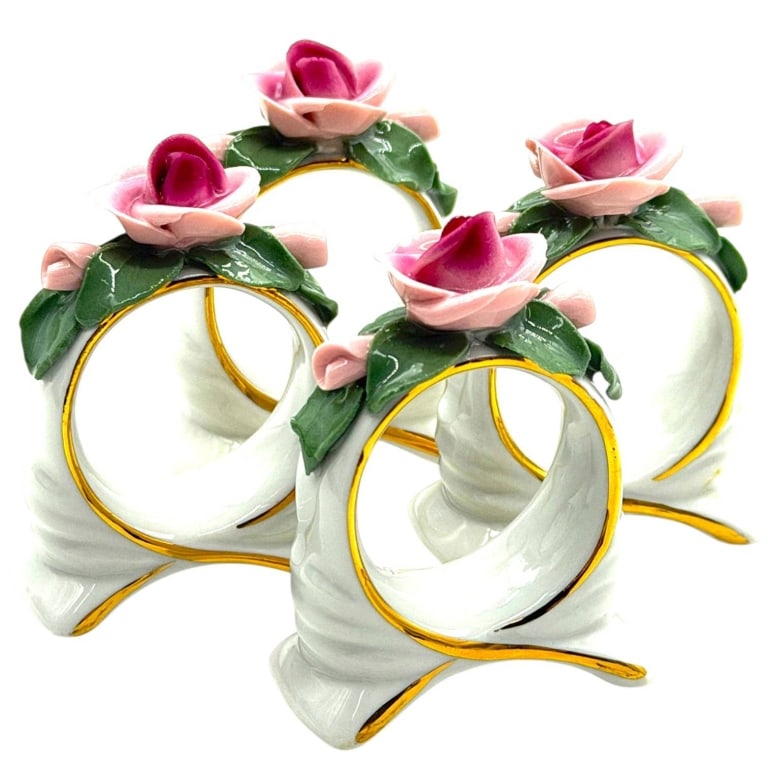 GERMAN PORCELAIN ROSE NAPKIN RINGS SET OF 4 2.25": Lovely set of four vintage German porcelain napkin rings, each modeled in glossy white porcelain with sweeping sculptural sides accented in hand-applied gold. Each ring is crowned by a dimensional por