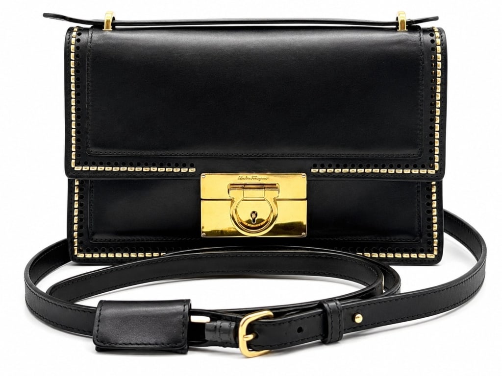 SALVATORE FERRAGAMO GANCINI BAG 10?: This Salvatore Ferragamo shoulder bag features smooth black leather accented with gold-tone metal detailing and the iconic Gancini turn-lock closure. The structured silhouette is enhanced by decorativ