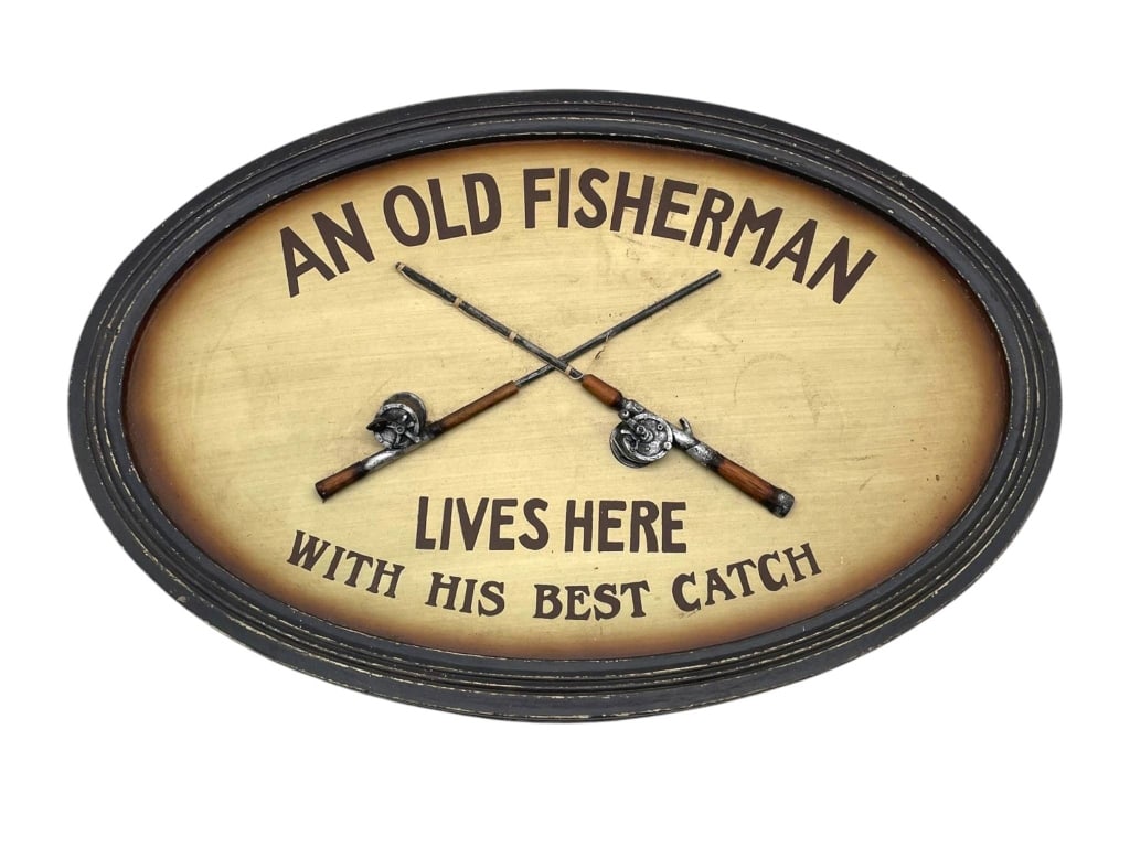 OLD FISHERMAN FISHING THEME WALL DECOR 23": Large oval decorative wall sign with rustic fishing theme, featuring the phrase "AN OLD FISHERMAN LIVES HERE WITH HIS BEST CATCH" across an antiqued cream-tone background. The face is embellished with