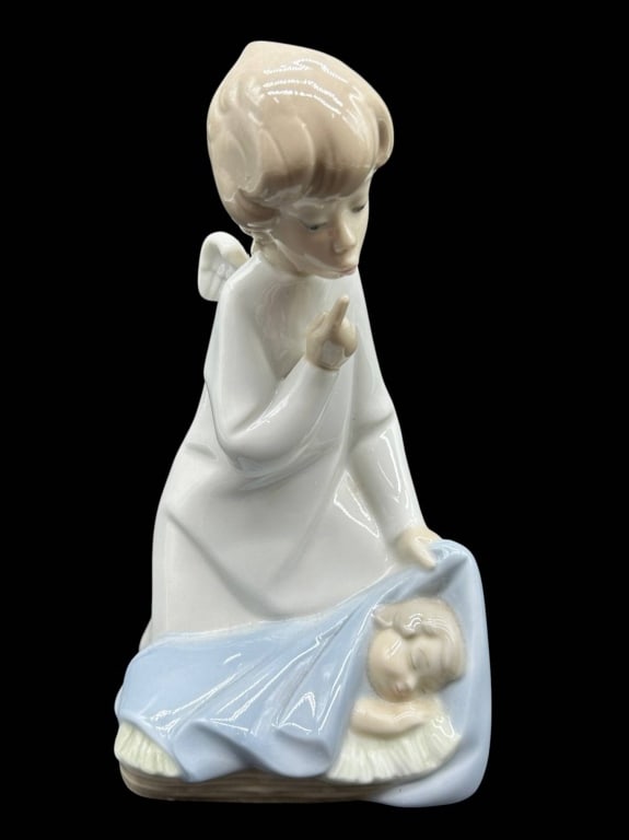 LLADRO ANGEL WATCHING SLEEPING CHILD 6.5": Charming vintage Lladro porcelain figurine depicting a guardian angel seated beside a sleeping child, gently lifting the child's pale blue blanket in a tender protective gesture. Rendered in Lladro's 