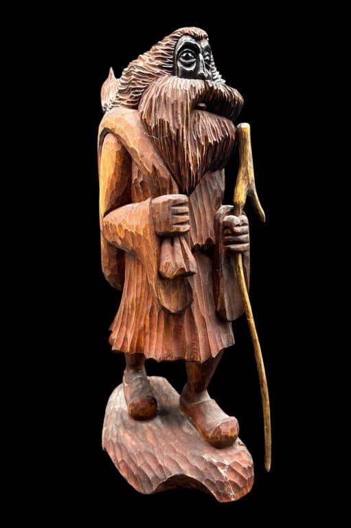POLISH CARVED WOOD WANDERER FIGURE 15": Hand-carved wooden folk art figure depicting a bearded traveler or wanderer standing with walking staff, wearing a long belted coat, boots and a large pack over his shoulder. The sculpture is extensiv