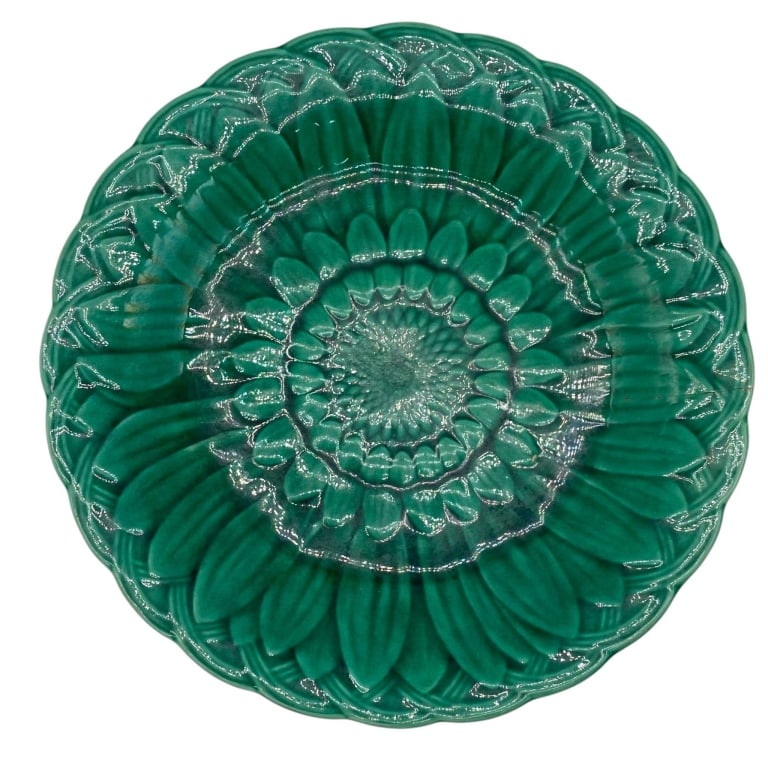 GREEN GLAZED FLORAL CERAMIC PLATE 9": Decorative ceramic plate featuring a rich emerald green glaze and deeply molded floral design arranged in concentric bands. The dimensional surface incorporates layered petals, leaves and stylized bot