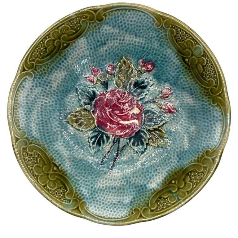 MAJOLICA ROSE FLORAL DECORATIVE PLATE 10": Decorative majolica-style ceramic plate featuring a richly molded bouquet of pink roses and rosebuds with layered blue-green foliage against a textured turquoise ground. The broad border is decorated 
