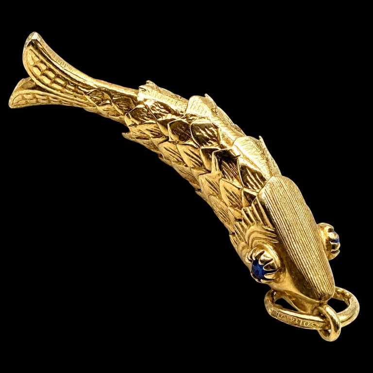 14K GOLD ARTICULATED FISH PENDANT BLUE STONE EYES: Finely crafted 14K yellow gold figural fish pendant featuring an articulated body composed of overlapping textured scales, allowing the pendant to move naturally. Detailed fins and tail complete the d