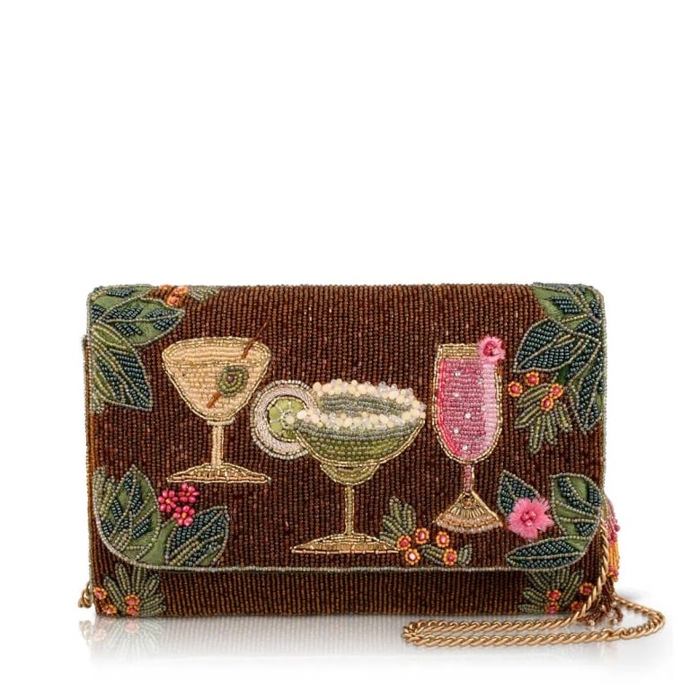 NEW MARY FRANCES CHEERS TO PARADISE BAG: Vacation mode is always within reach with Cheers to Paradise, a tropical handbag that captures the art of unwinding. Framed by vibrant botanicals, three festive cocktails invite you to slow down, sip 