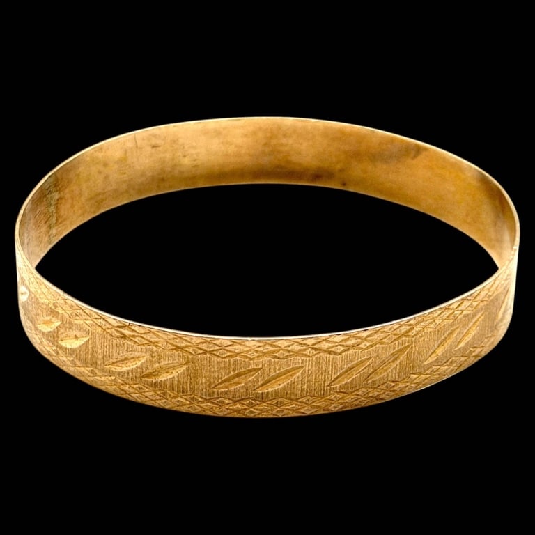 14K GOLD ETCHED GEOMETRIC BANGLE BRACELET: 14K GOLD ETCHED GEOMETRIC BANGLE BRACELET | | Elegant vintage bangle bracelet crafted in 14K yellow gold, featuring finely etched geometric, chevron, and foliate-inspired decoration across the exterio
