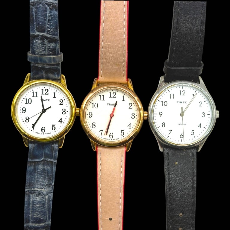 LOT OF 3 TIMEX INDIGLO WATCHES MEDIUM FACE 32MM: Lot of three classic TIMEX quartz wristwatches, each with an approximately 32mm case diameter and easy-to-read white dial with black Arabic numerals. Includes two gold-tone examples and one silver-ton