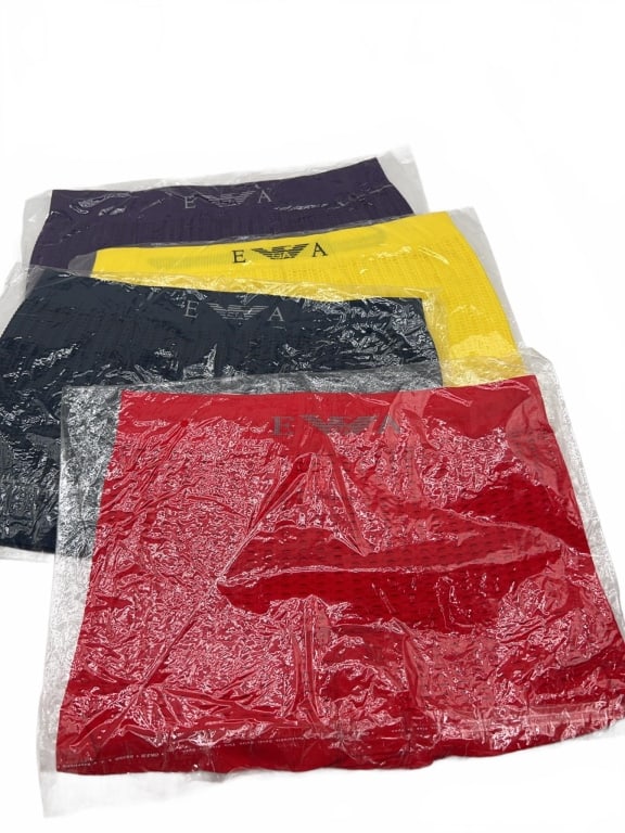 Emporio Armani Men's Boxer Briefs Set of 4: Four Emporio Armani men's boxer briefs in red, black, yellow, and purple. Each piece is individually packaged in plastic. Emporio Armani branding is visible on the waistband of each brief. Ruler not i