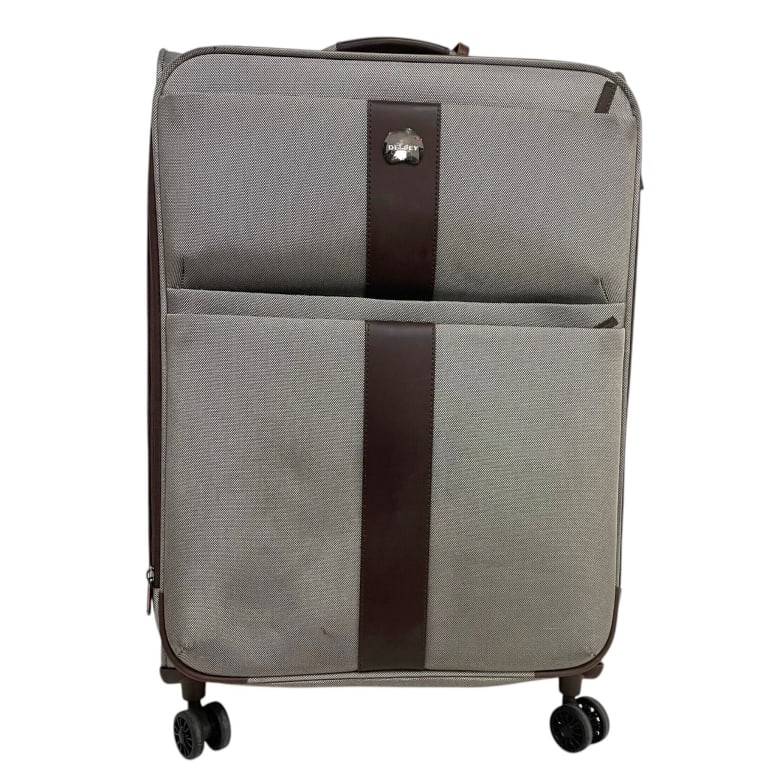 DELSEY LARGE SOFTSIDE SPINNER SUITCASE: DELSEY softside rolling suitcase featuring a durable taupe-gray woven textile exterior accented with dark brown trim and vertical detailing. Designed for extended travel, the case features a spacious 