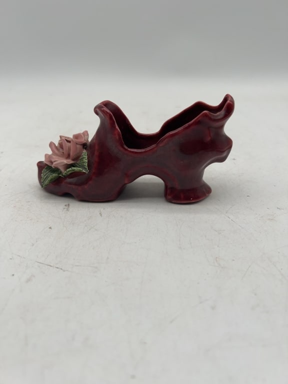 Ceramic Burgundy Shoe Planter with Flower Detail: Ceramic shoe-shaped planter in burgundy glaze featuring a pink flower and green leaf detail on one side. Measures approximately 5 inches in length and 3 inches in height. The item has a sculpted, deco