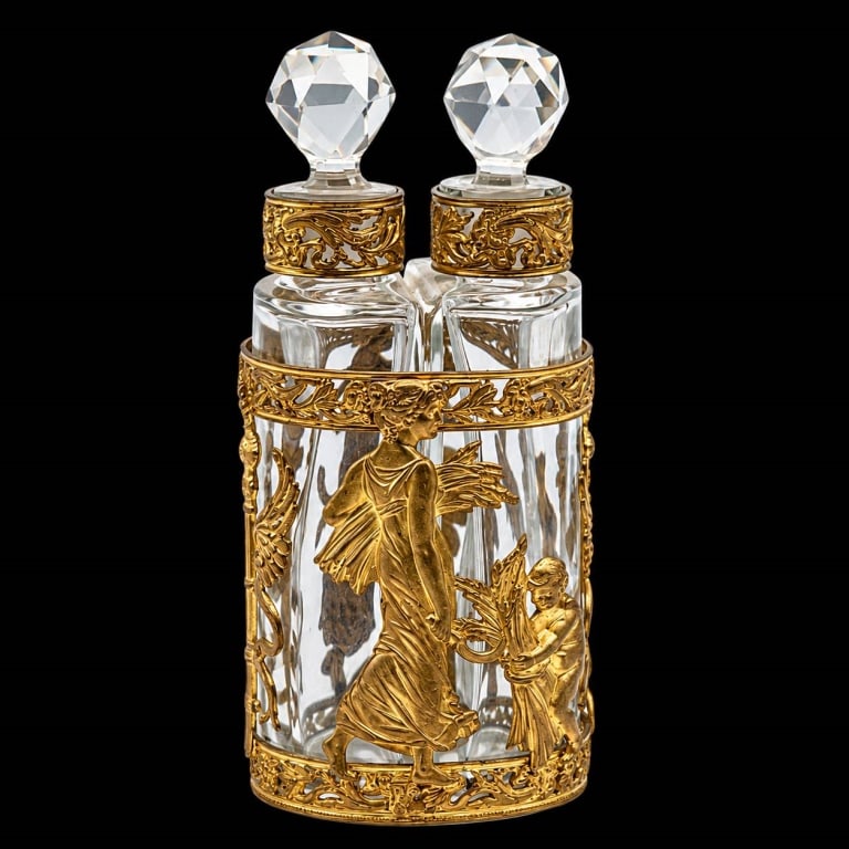 FIGURAL GILT METAL DOUBLE PERFUME BOTTLE SET 4": Elegant vintage double perfume bottle vanity set featuring two clear cut glass bottles held within an elaborate gilt metal openwork caddy. Each bottle is fitted with a faceted crystal stopper and an