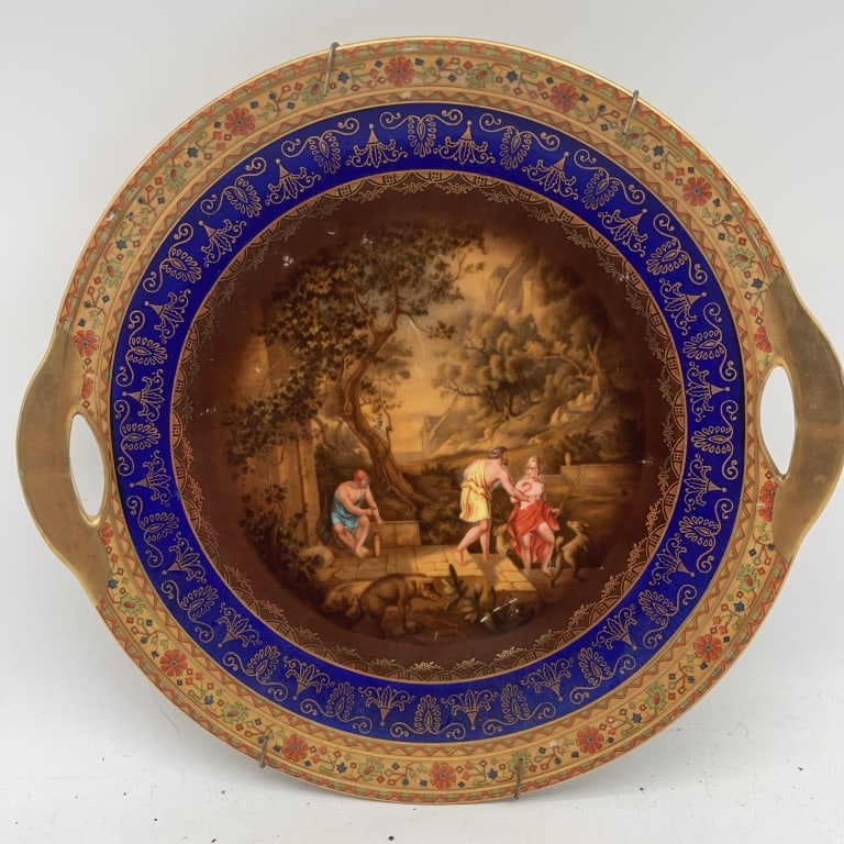 Hand-Painted Porcelain Tray with Handles: Decorative round porcelain tray featuring dual gold handles and an ornate hand-painted scene at the center, encircled by a cobalt blue band with gilt detailing. Measures approximately 12 inches in dia