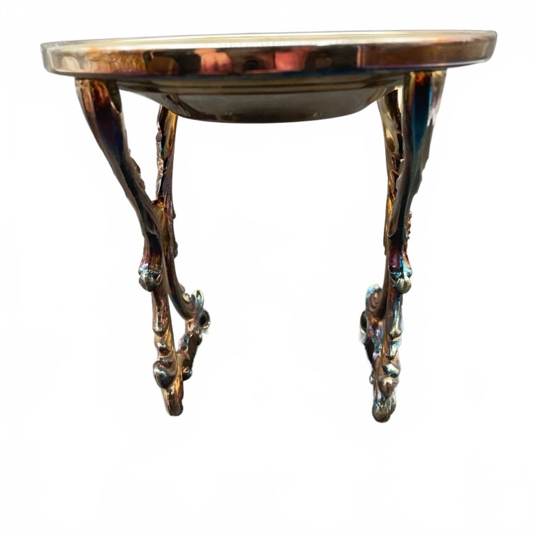 Metal Pedestal Stand with Ornate Legs: Ornate metal pedestal stand with curved decorative legs and a round top. The metal has a glossy finish with blue, gold, and bronze hues. Measures approximately 4.5 inches in height. The piece has no v