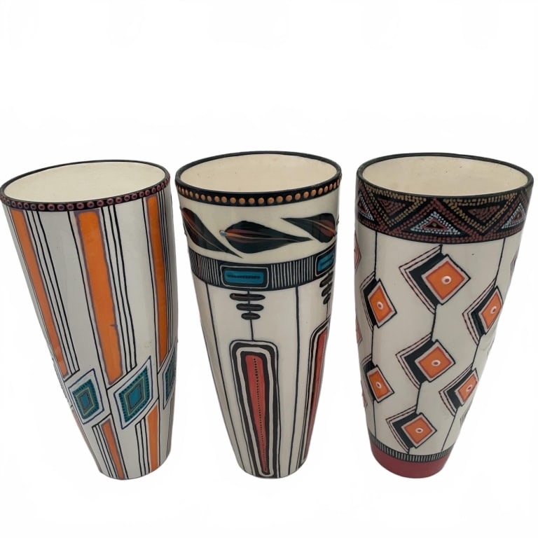 Three Geometric Pattern Ceramic Vases 12": Three ceramic vases featuring geometric designs in orange, blue, and black. Each vase displays unique hand-painted patterns and tall cylindrical forms. All vases have a glazed finish.
