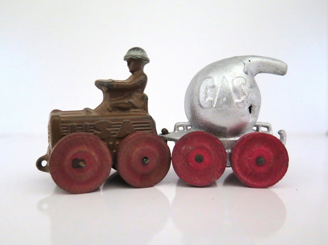 (2) Piece Manoil Pot Lead Fuel / Gas Trailer and: (2) Piece Manoil Pot Lead Fuel / Gas Trailer and Soldier Driving Tractor – Pre-War – Wooden Wheels (Checkers) – Some Wear and Fading Paint – Complete – 2 ¼” Tall (Tallest)