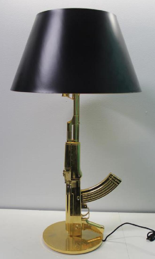 Philippe Starck. 'Kalashnikov AK-47' table light.: Philippe Starck. 'Kalashnikov AK-47' table light, c2005. H. 94 cm, D. 51.5 cm. Made by Flos, Milan. Gilded aluminium, black plastic/paper shade. Marked: happiness is a warm gun, with original box. Fro
