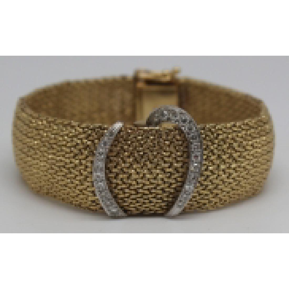 JEWELRY. Baume & Mercier 14kt Gold and Diamond: Watch. Baume & Mercier 14kt yellow gold bracelet with (2) bands of diamond accents and hidden watch face. (22) round diamond accents set in 14kt white gold. Baume and Mercier movement, 17 jewels; 