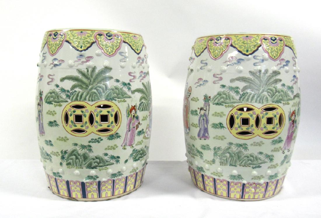 Pair of Famille Rose Enameled Garden Stools.: The pair decorated with scenes of immortals among landscapes, bordered top and bottom in stylized floral designs and pierced to sides and tops with cash symbols. Base with iron red six character Qianl