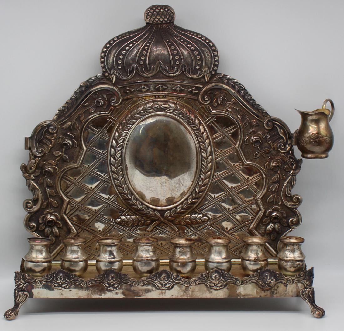 JUDAICA. Portuguese Sterling Menorah.: Portuguese sterling menorah comprised of a footed rectangular base and decorative back plate with central cartouche and laurel wreath surround, floral swags, and surmounted by a crown. With unmarked o