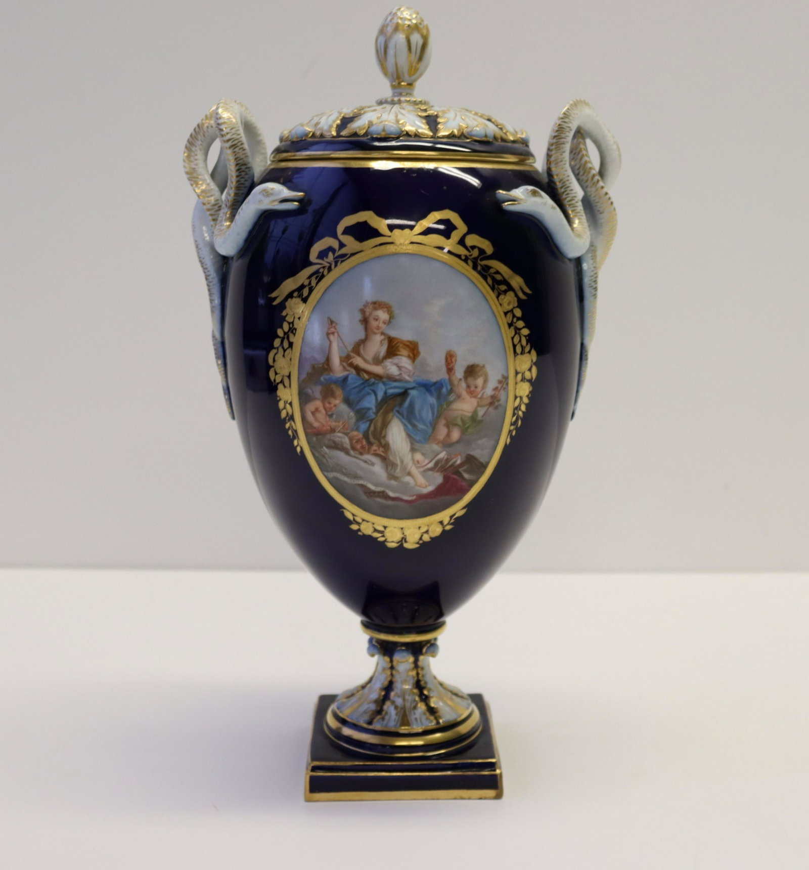 MEISSEN Double Snake Handles Potpourri Vase.: Hand painted Reserve with one side Drunken Silenus cherub feeding him goats by his feet and a satyrs to his side. Other side is Venus and Cupid with Bows in their hands. Gold bow Trim on either side. 