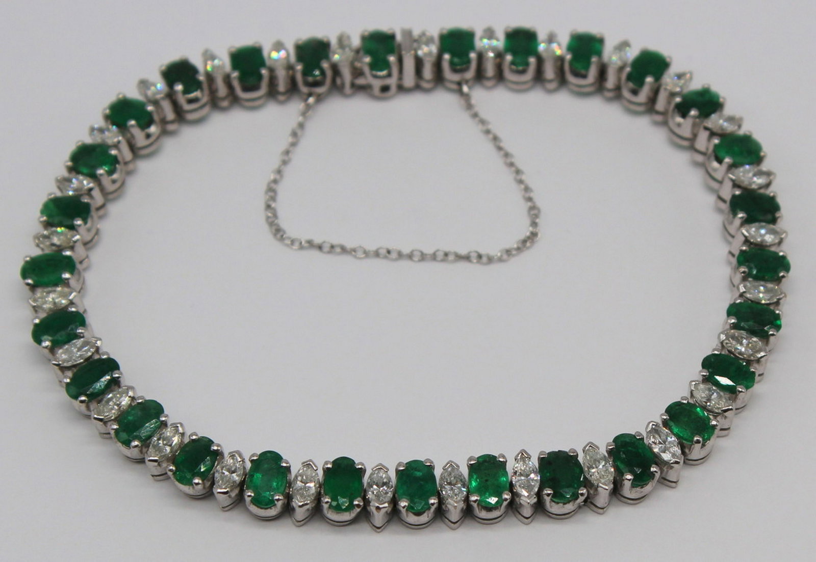 JEWELRY. Platinum, Diamond and Emerald Bracelet.: Platinum bracelet inlaid with (29) oval cut emeralds and (29) marquis cut diamonds. (29) oval cut emeralds measure approx. 4.5mm x 3mm, total approx. weight of 4.25 cts; (29) marquis cut diamonds meas