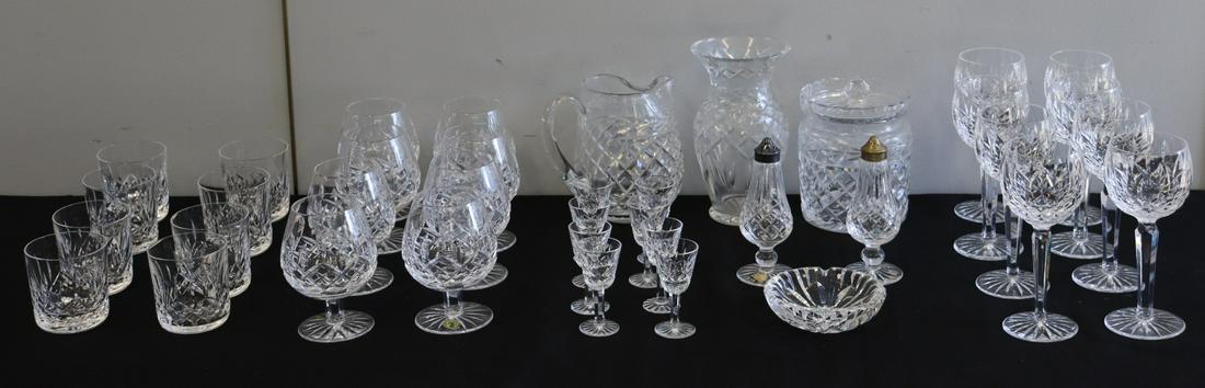 WATERFORD. Large Lot Of Assorted "Lismore": Cut Glass. To include lidded jar (6"x5"), 1 bowl (4.75"), 1 vase (8"), salt and pepper (6"), jug (6.5"), 8 wine glasses, 8 brandy glasses, 8 tumblers and 8 liqueurs. From