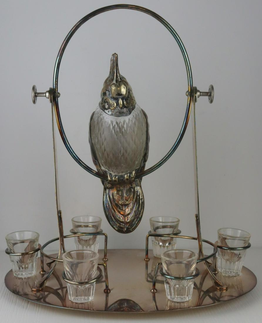SILVERPLATE. Parrot Form Silverplate Decanter Set.: Unusual silverplate bar set comprised of a silver plate and etched glass parrot form decanter seated in a hinged swing. Swing is set on an oval base with (6) shot glass holders, and (6) shotglasses. A