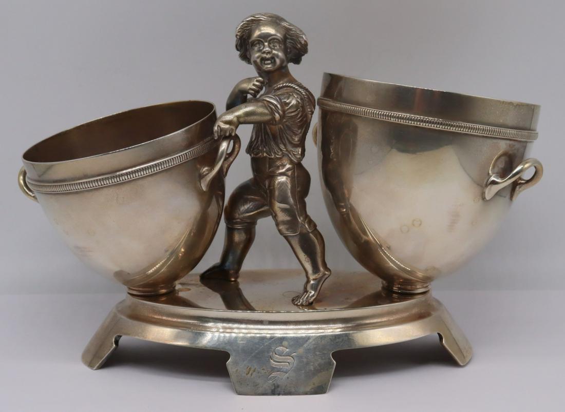 STERLING. Early Gorham Figural Stand with Two: Vessels. 19th century Gorham sterling stand with central standing figure of a boy flanked by two cups with handles. Stamped to underside with Gorham pictorial hallmarks, a date letter of "C" represent