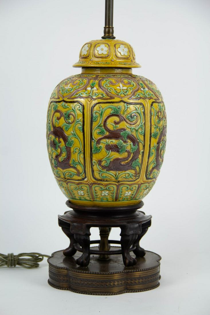 A 20th Century Sancai Ginger Jar as a Lamp.: Carved with chilong and plum blossoms and glazed in shades of amber, brown, green, and white. Mounted on a carved claw foot base over an early 20th century metal base. From a White Plains, NY estate. 