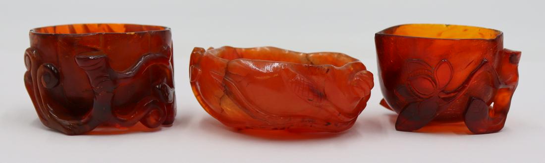 Carved Amber and Carnelian Water Coupes.: (1) carved amber water coupe decorated with a vine and leaves; and a second carved amber water coupe decorated with a leafy branch and a butterfly. Accompanied by a foliate decorated carved Carnelian 