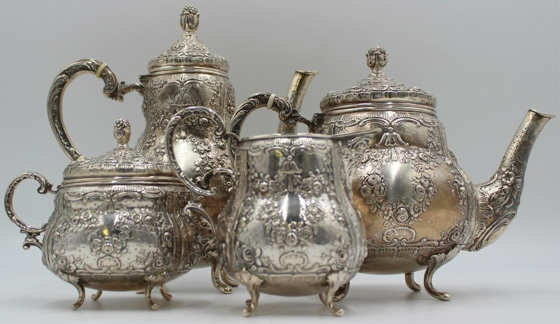 SILVER. 4 PC. German .800 Silver Repousse Tea Set.: Comprised of a footed teapot, footed coffee pot, footed creamer, and a footed lidded sugar. All items decorated with elegant floral repousse work, acorn finials and blank cartouches for one's own mono