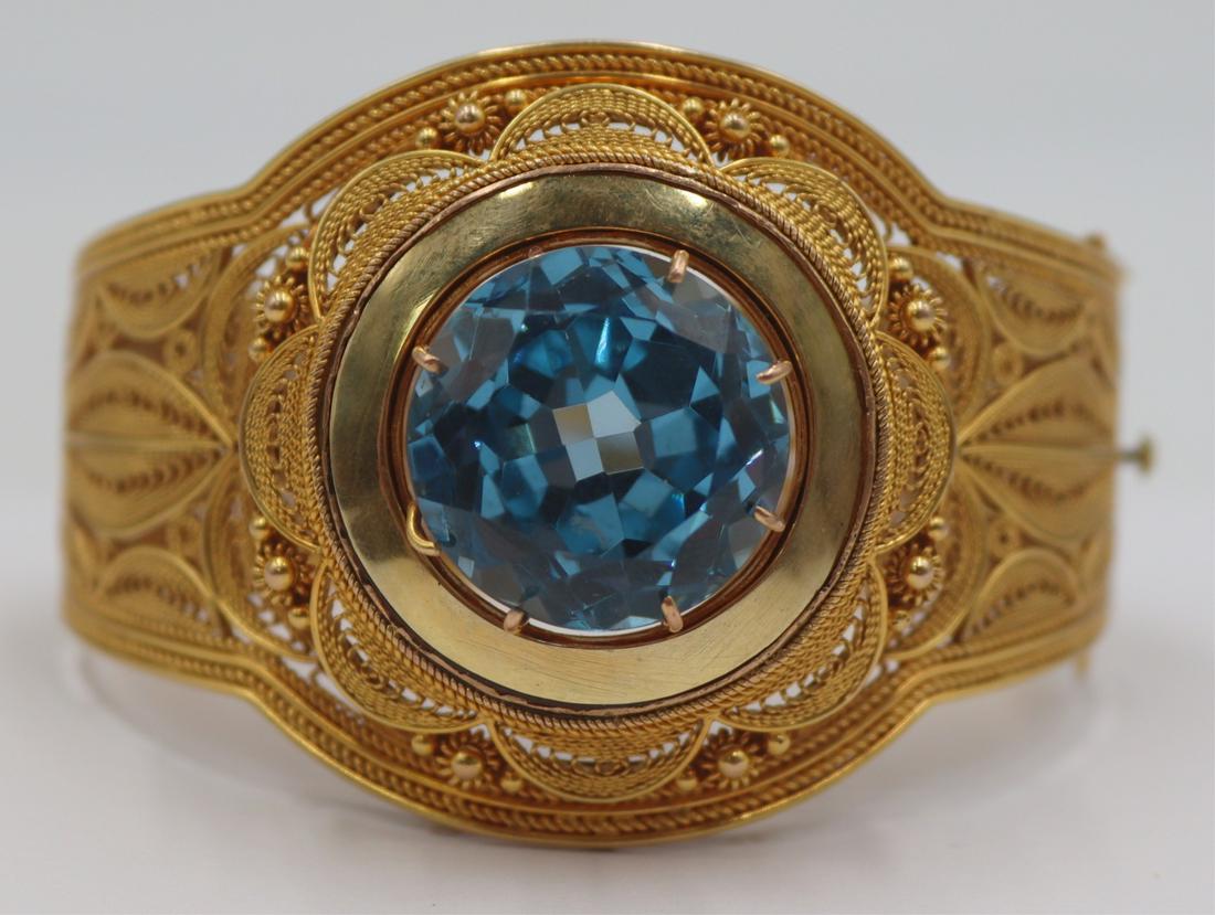JEWELRY. 14kt Gold and Colored Gem Bracelet.: Beautiful 14kt yellow gold filigree hinged bracelet with large central round faceted colored gem. Possibly Israeli? With (2) illegible numerical stamps, and (3) undetermined pictorial hallmarks. Color