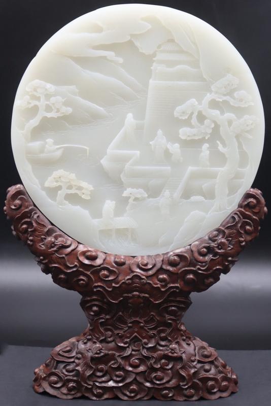 Chinese Carved High Relief Jade Disc on Stand.: Chinese carved circular jade disc with high relief depiction of figures in a garden pavilion with trees and clouds; alternate side decorated with a high relief depiction of a cherry blossom tree. Acco