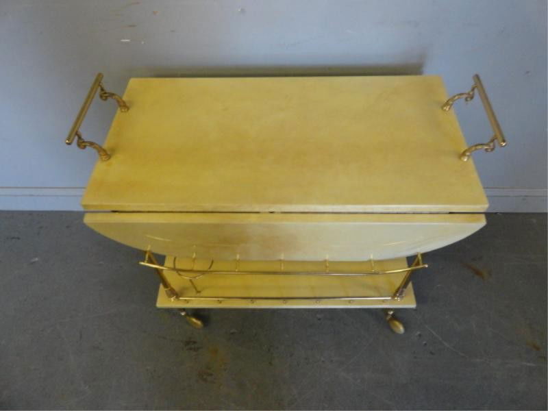 ALDO TURA Brass and Goatskin Rolling Bar Cart.: 2 tiered with 2 drop leaves. Bottle storage on lower shelf. Midcentury. From a Long Island estate. Dimensions: 26.25" high (+ handles) x 16.25" closed/30.75" open. From a Long Island estate.