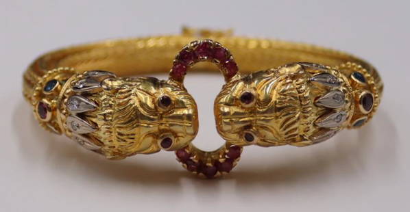 JEWELRY. Ilias Lalaounis 18kt Gold Diamond and Gem: Lion's Head Bracelet. Signed Ilias Lalaounis 18kt yellow gold hinged bracelet displaying two colored gem and diamond inlaid lions' heads suspending a colored gem inlaid ring within their mouths. Stamp