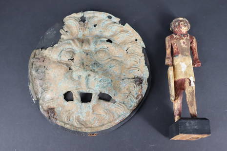 Lot Of 2 Antiquities Including Egyptian &amp; Roman.: A mounted Roman bronze Lion head plaque with some gilt remnants and an Egyptian wood figure on base. From a Sutton Place, NYC estate. - Dimensions: 9" dia & 9" h.