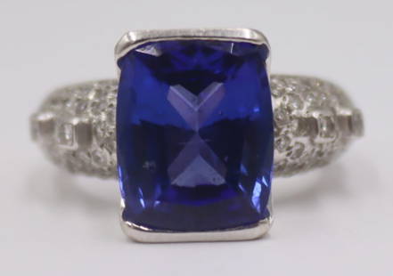 JEWELRY. 18kt Gold, Gem and Diamond Ring.: 18kt white gold cocktail ring displaying a central oval faceted colored gem, possibly Tanzanite, flanked by pave diamonds and (4) additional bezel set round faceted diamonds. Colored gem measures appr