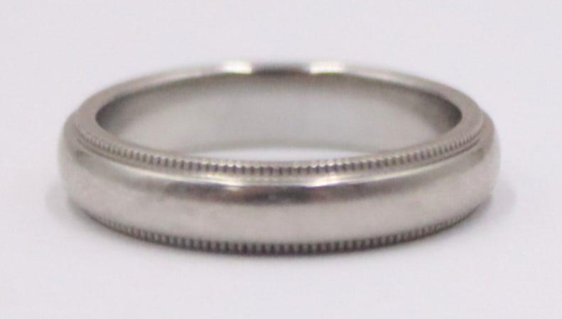 JEWELRY. Tiffany & Co. Platinum Wedding Band.: Tiffany & Co platinum wedding band with milgrain borders. Inscribed, "Tiffany & Co. PT .950". Total approx. weight of the ring is 4.6 dwt (gross). Ring size - 5 1/2. From a Norwalk,