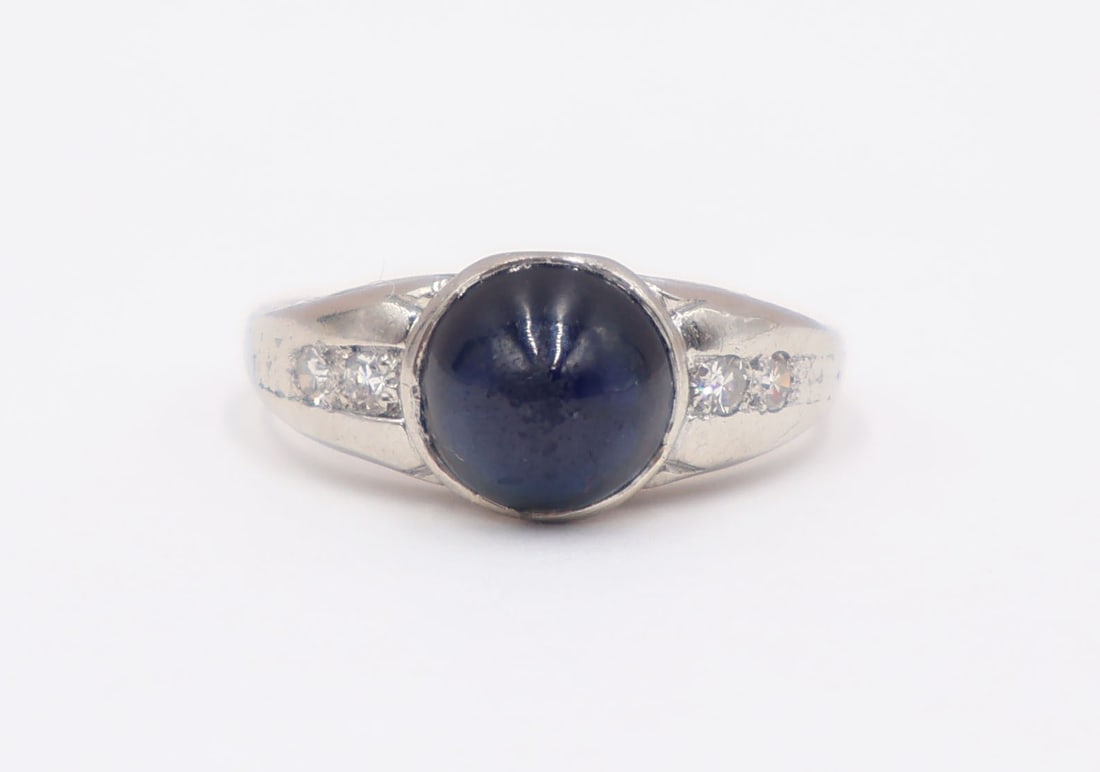 JEWELRY. Sugarloaf Sapphire, Diamond and Platinum: Ring. Platinum ring displaying a central sugarloaf sapphire flanked by a total of (4) single cut diamond accents. Sapphire measures approx. 7.0mm. Apparently unmarked. Total approx. weight of the ring