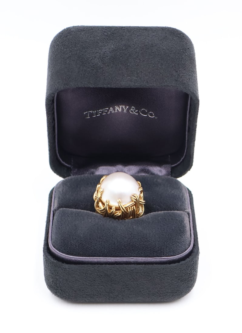 JEWELRY. Tiffany & Co. 18kt Gold and Mabe Pearl: Ring. Tiffany & Co. 18kt yellow gold foliate form ring displaying a central mabe pearl. With a plaque to the underside stamped, "Tiffany & Co". Accompanied by a Tiffany & Co. hin