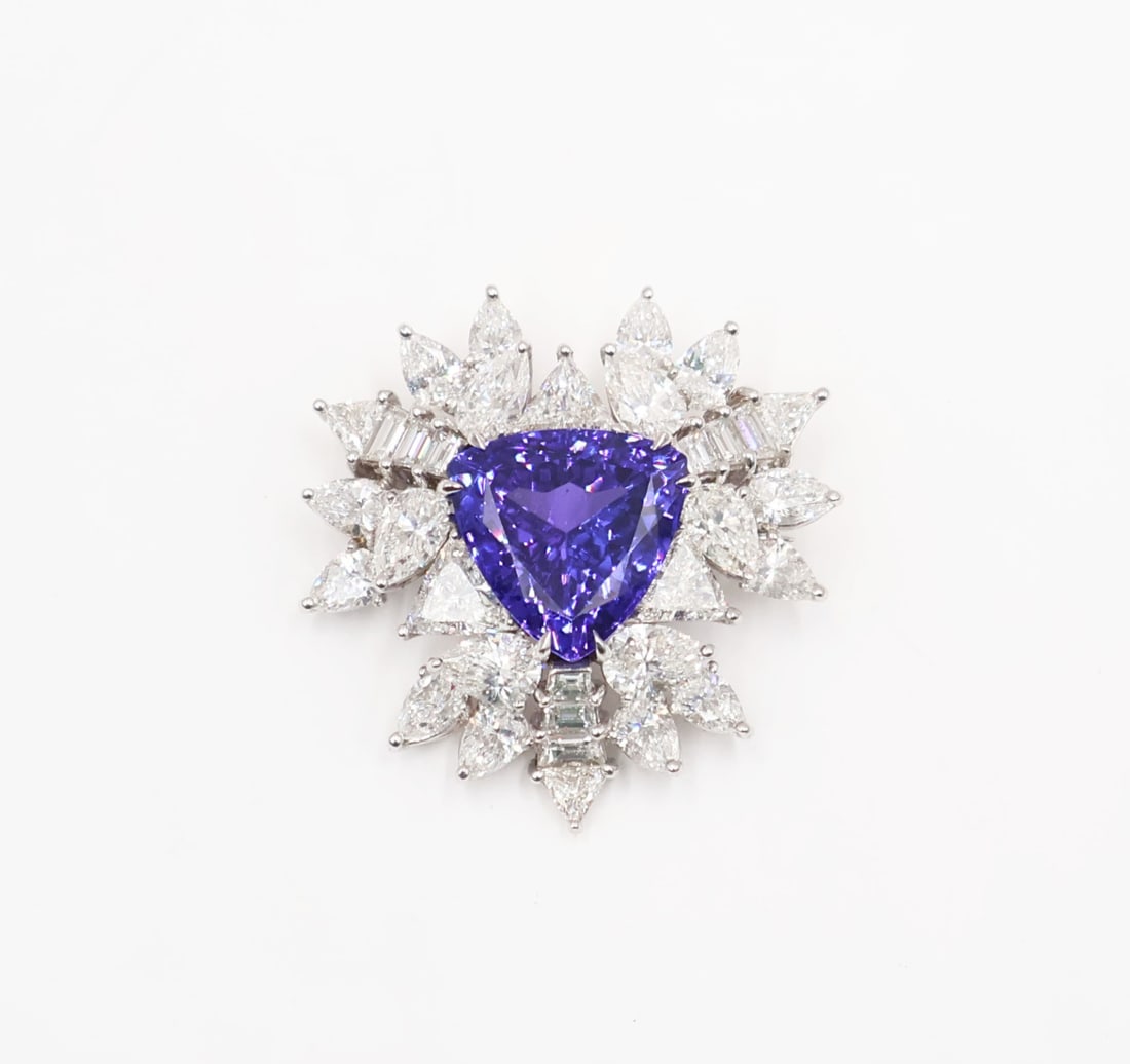 JEWELRY. Kantra Platinum Tanzanite and Diamond: Pendant. Signed Kantra platinum brooch displaying a central prong-set 9.64 faceted Tanzanite surrounded by (18) pear faceted diamonds, (6) trilliant cut diamonds, and (9) tapered diamond baguettes. To