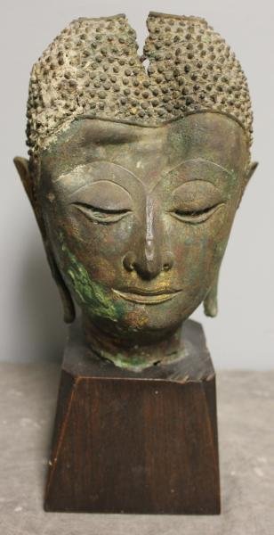 Southeast Asian Gilded Bronze Buddha Bust.: On a wood stand. Possibly very early. From a Mamaroneck, NY estate. Dimensions: Without stand - 7.75" high; With stand - 11.75" high. Condition: Most gilding gone; significant dent to front and loss i