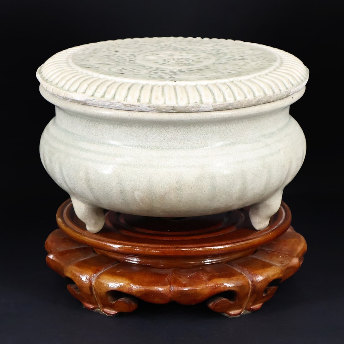 Vietnamese Tran Dynasty Celadon Lidded Censer.: A footed censer with a lobed body and a lid with a fluted rim and incised central medallion of a dragon surrounded by flowers. With a footed wooden stand. Accompanied by a March 17th, 2019 Zetterquist