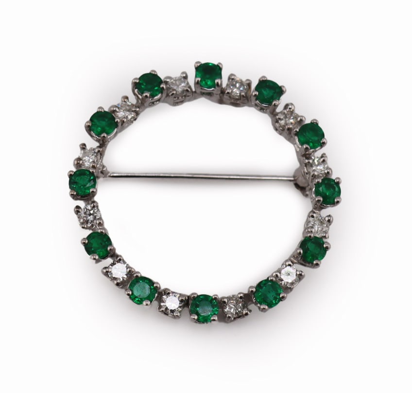 JEWELRY. 15ct Gold, Emerald and Diamond Brooch.: 15ct white gold circular openwork brooch displaying a total of (12) round faceted emeralds alternating with (12) round faceted diamonds. Emeralds measure approx. 3.0mm each; diamonds measure approx. 2