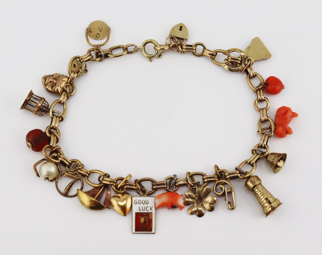JEWELRY. 14kt Gold Charm Bracelet with (20) Charms: 14kt yellow gold charm bracelet suspending a (1) 14kt heart form lock and key; (1) 14kt gold Buddha; (1) 14kt horseshoe; (1) salmon coral heart; a salmon coral dog; (1) 14kt gold bell inscribed, "