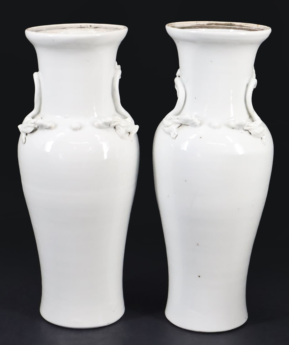 Pair of Chinese Dehua Vases.: A pair of Chinese blanc de chine vases displaying qilins wrapped around the neck chasing a ball. Apparently unmarked. From a Manhattan, NY estate. Dimensions: both measure approx. 11.5" in height