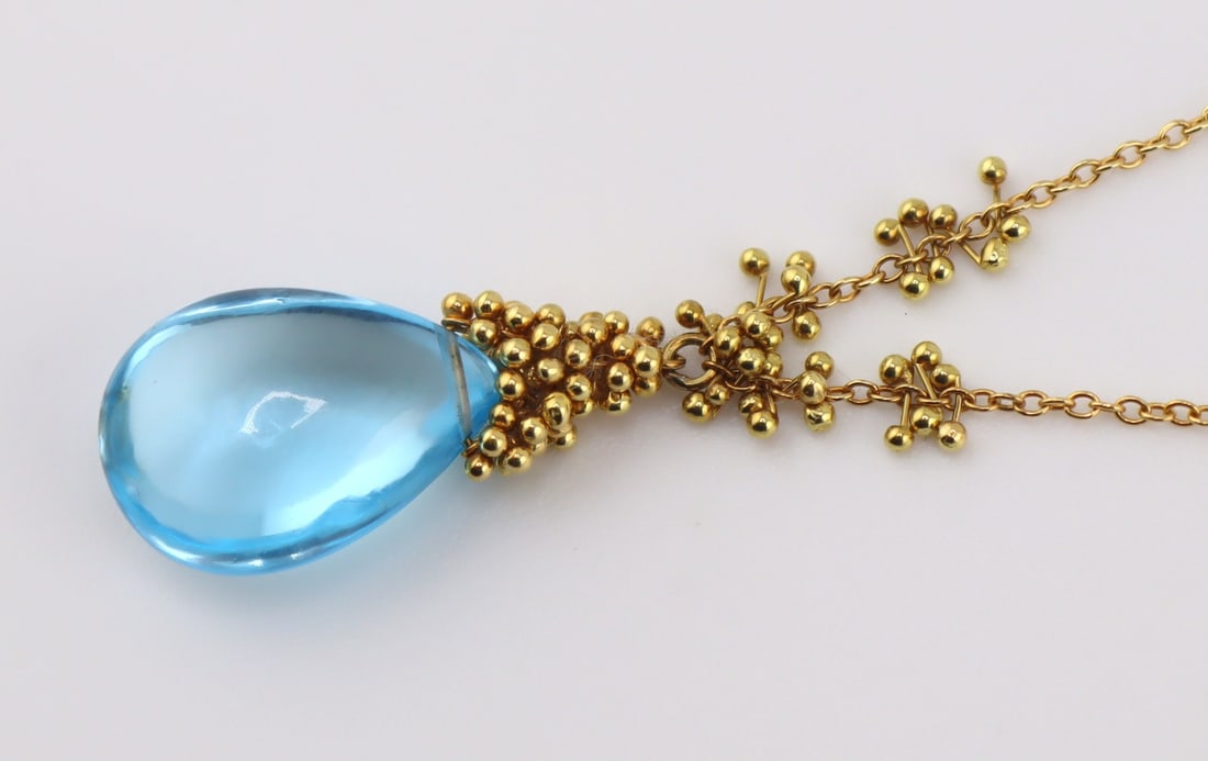 JEWELRY. 18kt Gold and Blue Gem Necklace.: 18kt yellow gold oval link petite necklace suspending a single polished pear form blue gem, presumably blue topaz, accented by beading. Gem measures approx. 10mm x 14.0mm x 6.0mm. Stamped, "750&q
